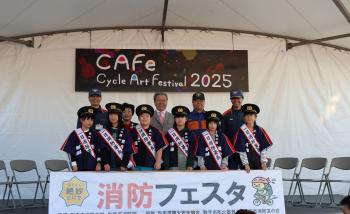 消防フェスタと書かれた看板の前で立つ子どもたちと大人の男性