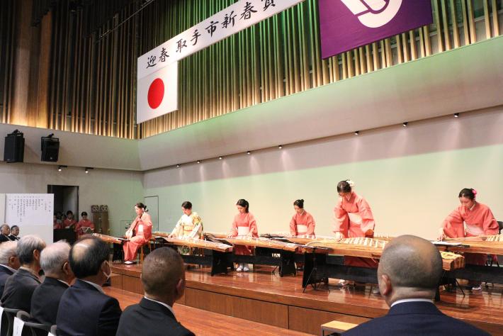 着物を着た女性がステージ上で琴を弾いている