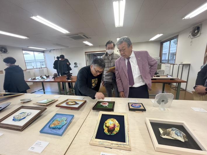 机に置かれた美術品を鑑賞する男性たち