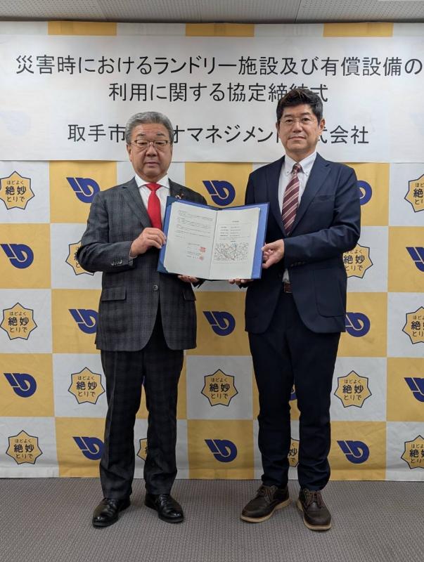 協定書を中央に持って立つ男性2名