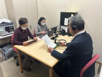 ヘットフォンをした男性がマイクに向かい合って話をしている