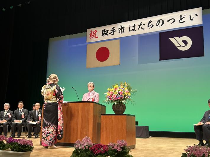 着物を着た女性が壇上で話をしている