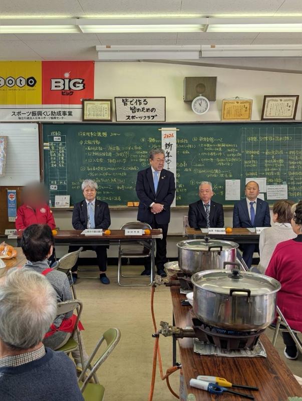 椅子に座る人たちの前に立ってあいさつをする男性