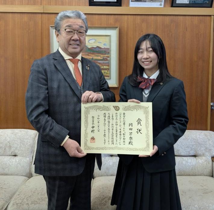 表彰状をもって立つ男女