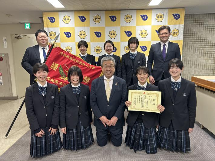 パネルの前で立つ女子生徒と男性教師