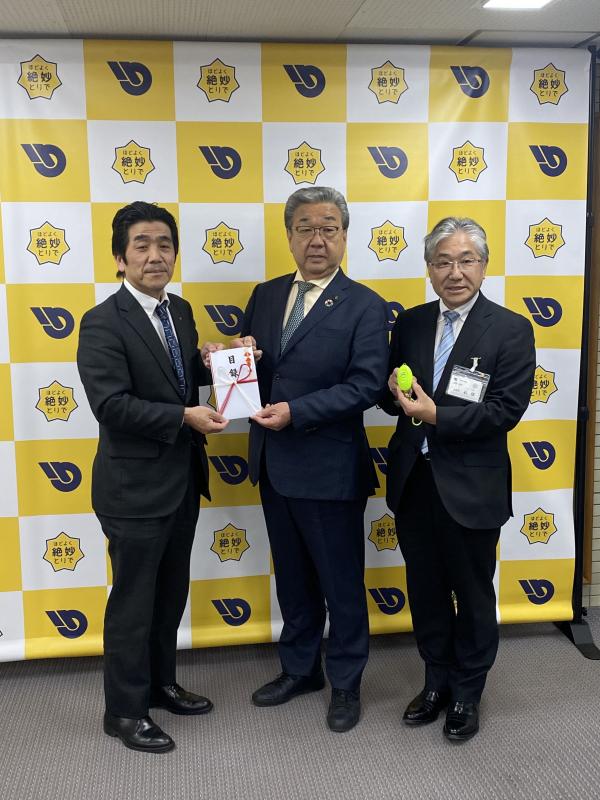 パネルの前で目録と防犯ブザーを持つ男性たち