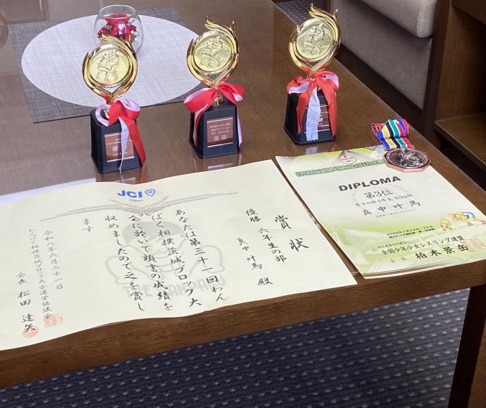 3つの優勝カップと賞状が机に並んでいる