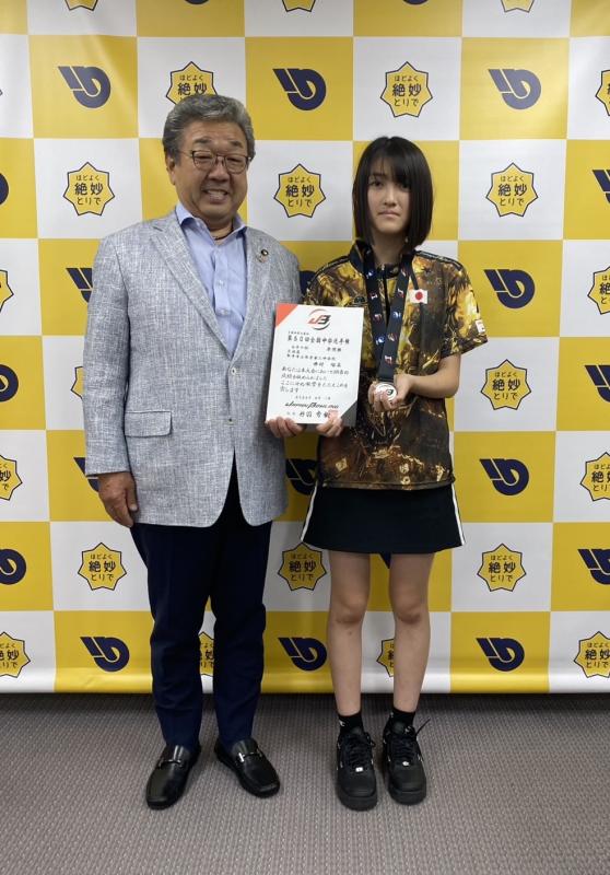 賞状を持って立つ女の子とスーツを着た男性