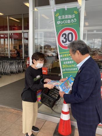 女性に啓発グッズを渡すスーツを着た男性