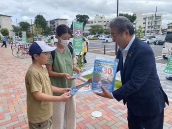 親子に啓発グッズを渡すスーツを着た男性