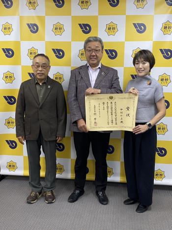 パネルの前に立つ男性2名と女性1名