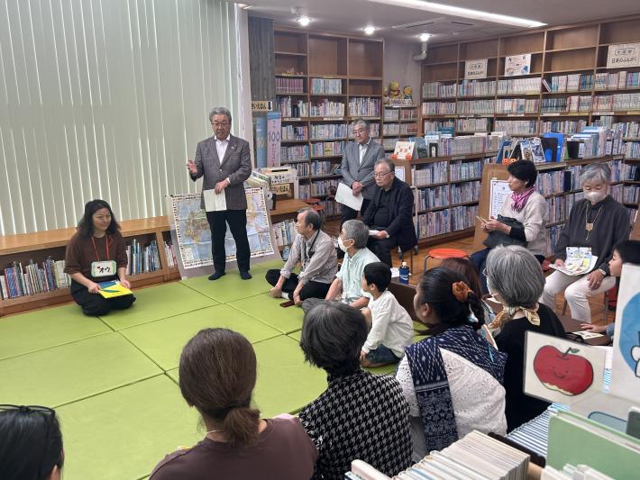 座っている人たちに向けてあいさつをする男性