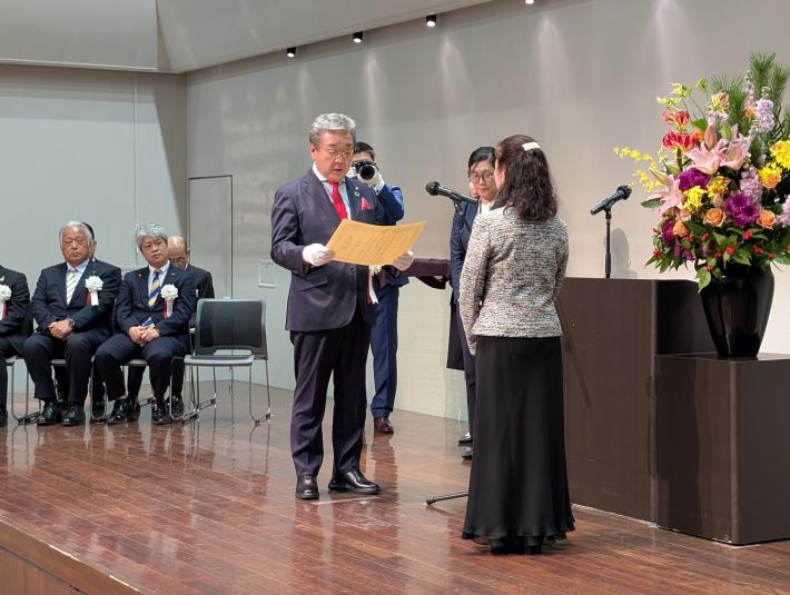 ステージ上で表彰状を渡す男性