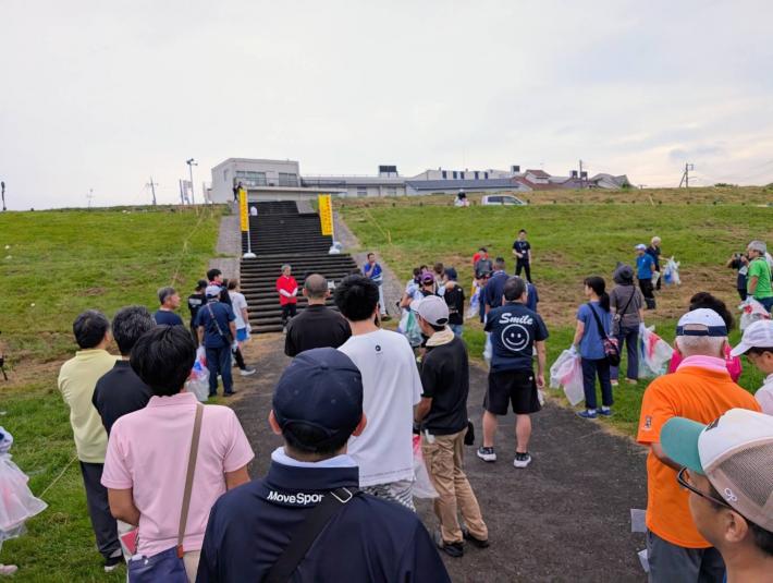 緑地に集まった方々の前で挨拶をする男性