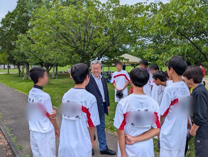 白いユニフォームを着た学生たちと話す男性