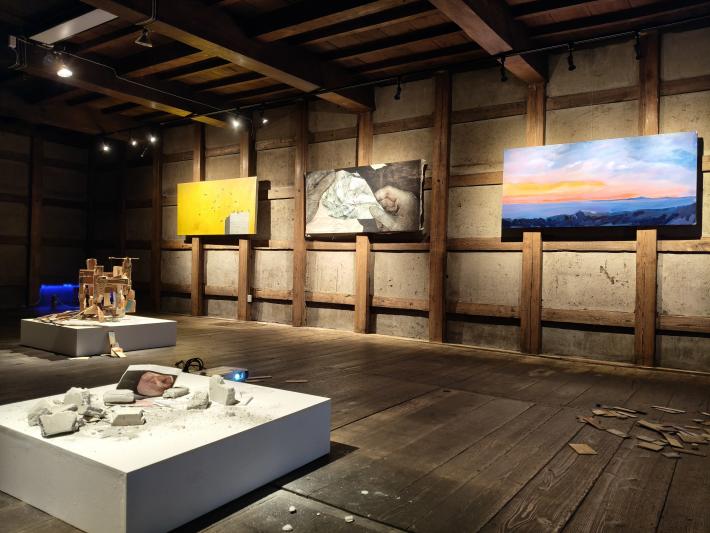 蔵の床に立体作品、壁に平面作品が飾られている会場の様子。