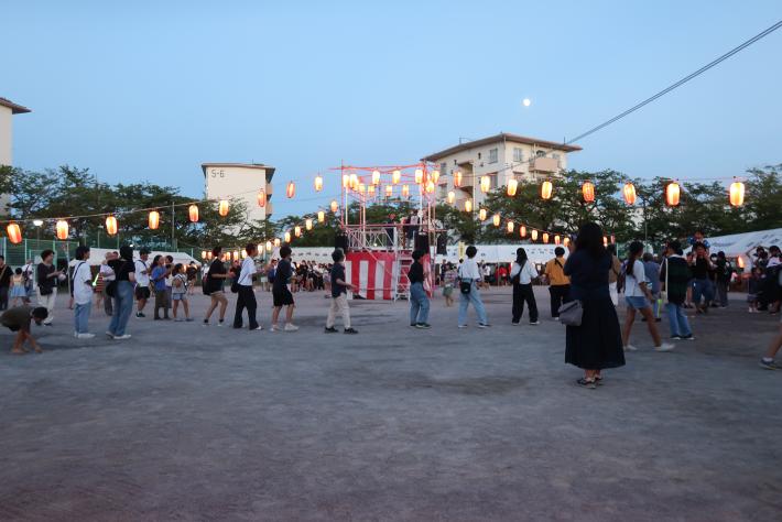 お祭りの会場に数十人が集まり、盆踊りを踊っている様子