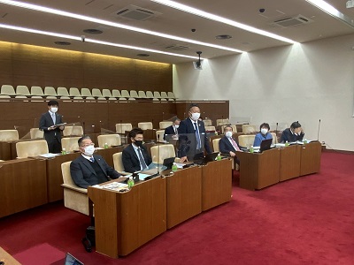 議席前から2列に筑西市議が座っている。最前列中央の男性議員が起立してあいさつをしている。