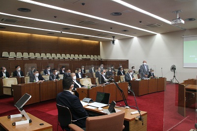 ほぼ全議席に座る大分県市議会議長会研修参加者。手前の質疑席には取手市議会事務局職員1名が座る。灰色のスーツを着た男性が起立する