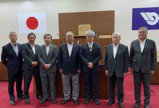議場で数人の男性議員が横に立って並んでいる