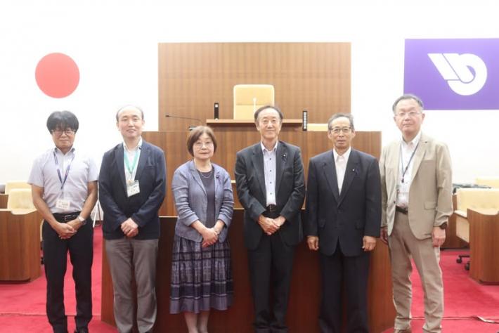 議場で数人の男性と女性が横に並んでいる