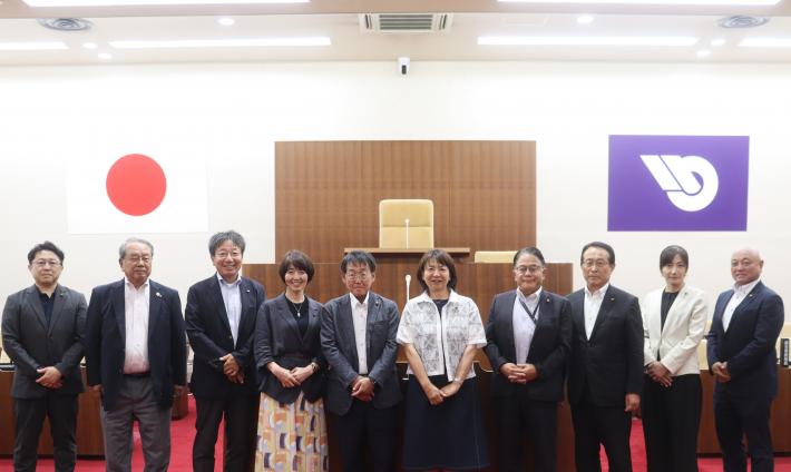 議場で数人の男性と女性が立って横に並んでいる
