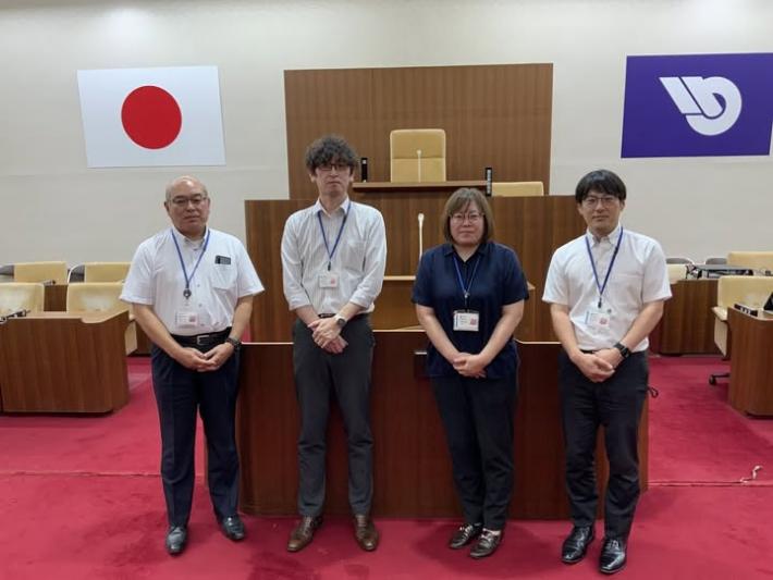 議場に3名の男性と1人の女性が並んで立っている