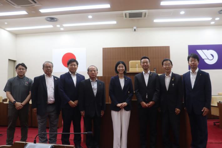 議場に男性と女性の議員数名が並んで立っている