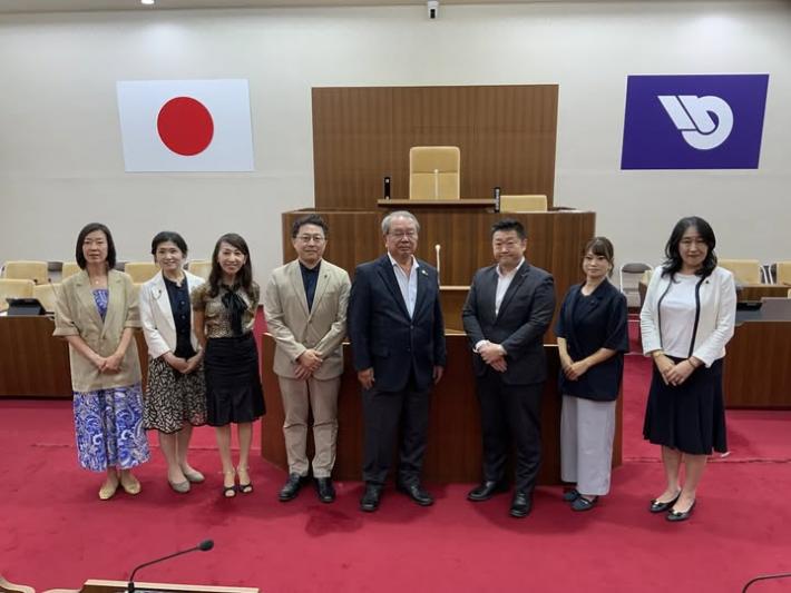 議場で男性と女性の議員数名が並んで立っている