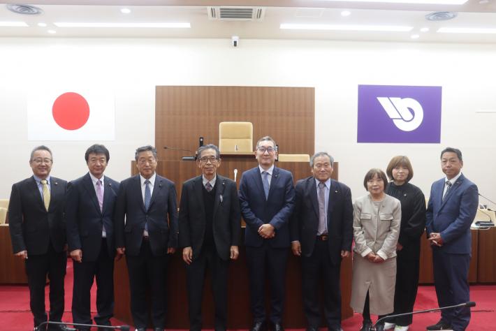 議場で男性と女性の議員数名が立って横に並んでいる