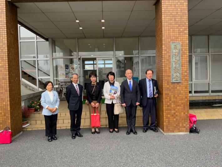 議会棟の入り口で男性と女性の議員数名が立って横に並んでいる