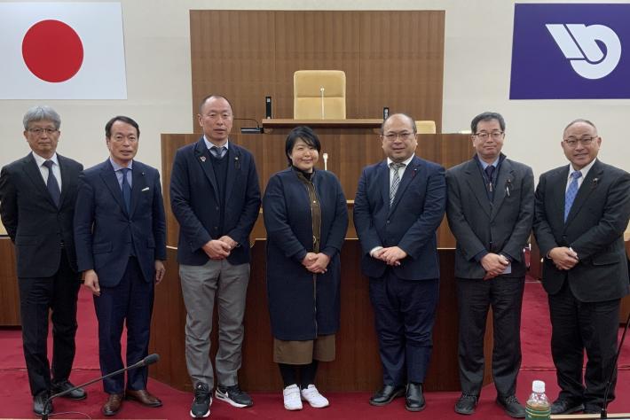 男性と女性の議員数名が議場で並んで立っている