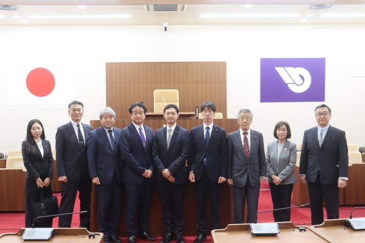 議場で男性と女性の議員数名が立って並んでいる