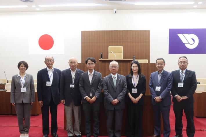 議場で男性と女性の議員数名が立って並んでいる