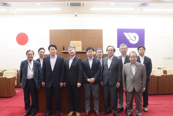 議場で男性の議員数名が立って並んでいる