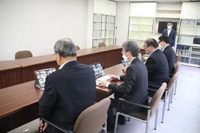 横一列に議員4人が座る。一人一台タブレットがあり、それぞれがオンライン会議に入る。一番奥に事務局職員1人が立つ