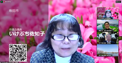 Zoom画面上に眼鏡をかけた短髪の女性が映っている。女性の背景にはピンクの花のバーチャル背景が映っている