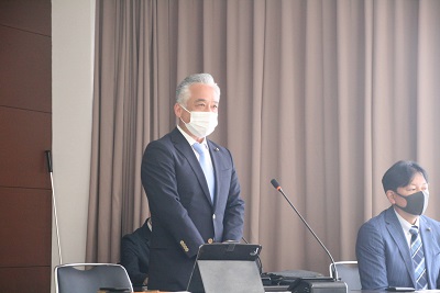 金澤議長が自席で起立し、歓迎のあいさつをしている。隣には佐藤委員長が着席。