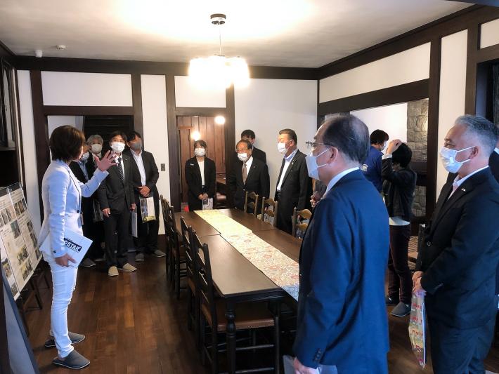 旧渡辺甚吉邸の室内で、職員の説明を議員数名が立って聞いている