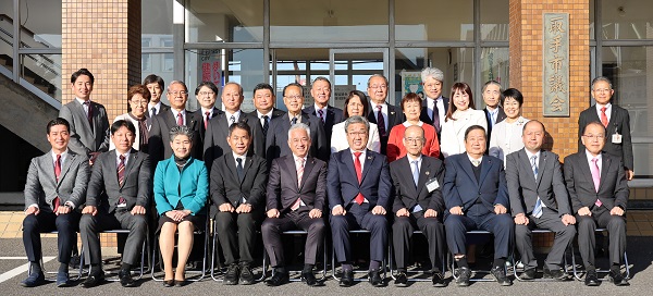 議会棟前で撮った集合写真。最前列10人が座り、後ろは立つ。議員全員と市長、教育長、議会事務局長が写る。