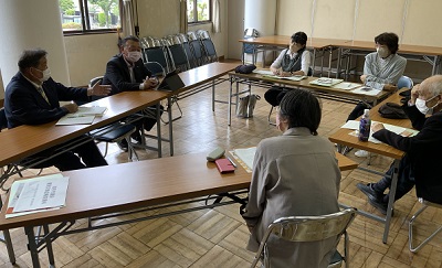 3つの縦長の机が三角形に置かれ、男性3名と女性3名が向かい合って座っている