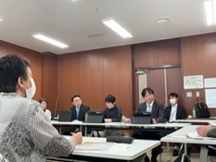 会議室で男女の議員が机に座って、数名の市民から意見を聞いている