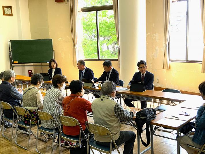 会議室で男女の議員が机に座って、数名の市民から意見を聞いている