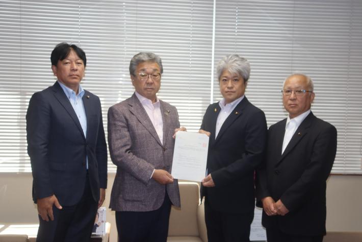 提言書を山野議長から中村市長へ手渡した後、山野井議長、中村市長、小堤副議長、佐藤委員長の4人で提言書を手に撮影した様子