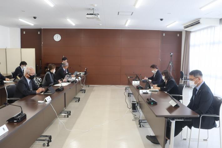 会議室で男女数名の議員が椅子に座って会議を行っている