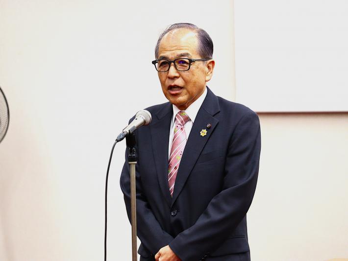 男性の議員が立ってマイクを使って話している