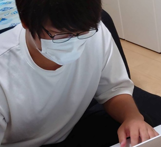 白い洋服を着た男性がパソコンを見ながらキーボードを打っている