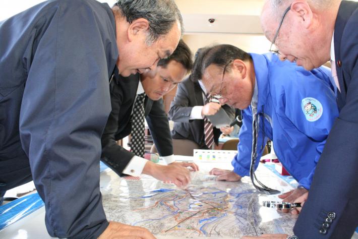 男性議員4人(竹原・渡辺・入江・赤羽議員)が机の中央に置かれた地図に書き込んでいる。