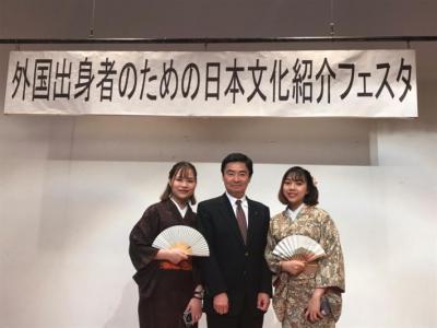 日本文化紹介フェスタの看板を背に、市長が着物姿の参加者2名の中央に立っている様子