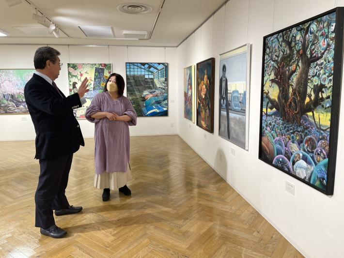 展示された絵画を見る市長と女性